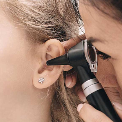 Audiologist with an otoscope looking in a patient's ear.